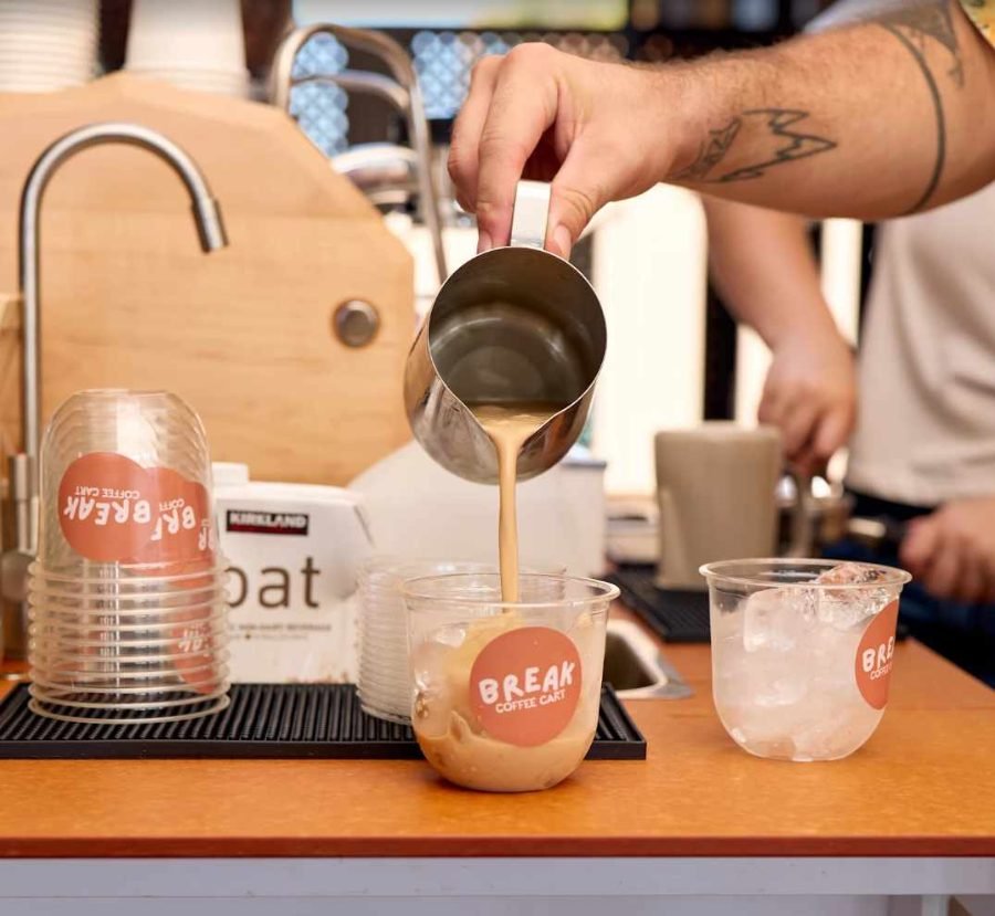 Barista pouring an iced Break Coffee Cart latte at a wellness event